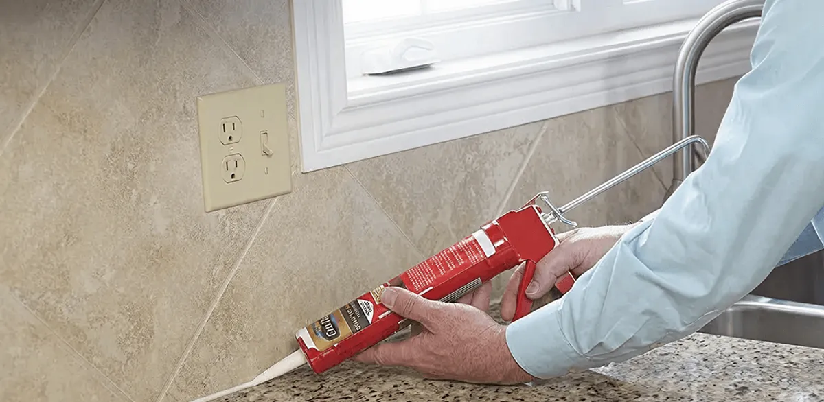 Handyman applying caulk along a kitchen backsplash and countertop seam in Wichita, KS