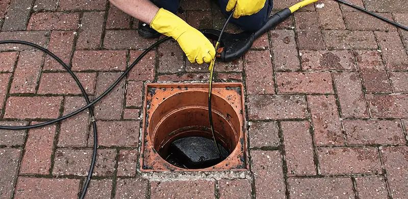 Drain cleaning technician using a drain snake to clear a clogged drain in Wichita, KS