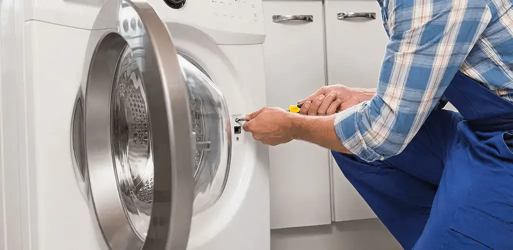 Handyman repairing a clothes dryer and checking electrical connections in Wichita, KS
