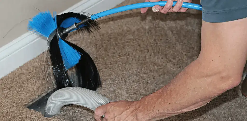 Dryer vent cleaning technician brushing lint from a vent line in Wichita, KS