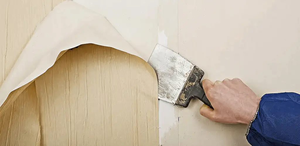 Handyman removing wallpaper with a scraper for wall preparation in Wichita, KS