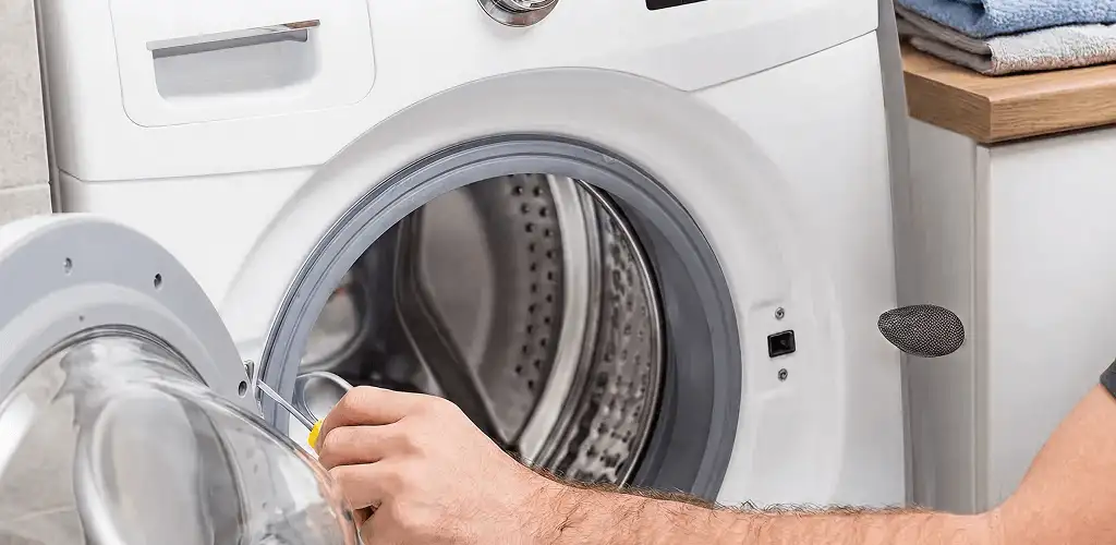 Handyman repairing a front-load washing machine and inspecting the drum in Wichita, KS