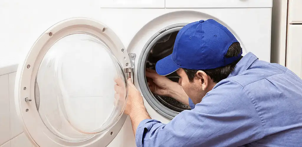 Washing machine repair handyman inspecting a front-load washer drum in Wichita, KS