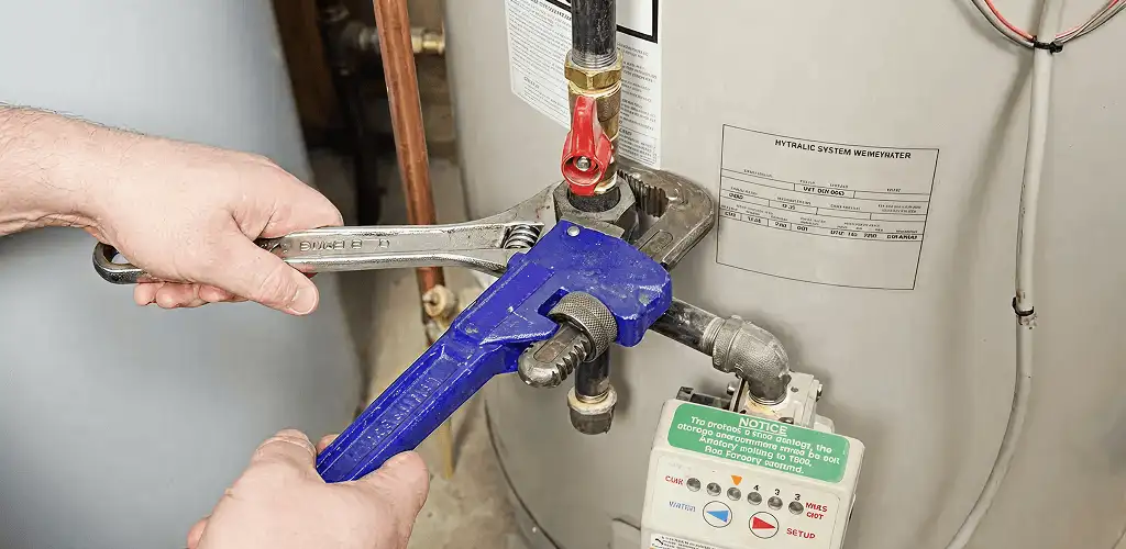 Water heater repair technician tightening the shutoff valve and supply line in Wichita, KS
